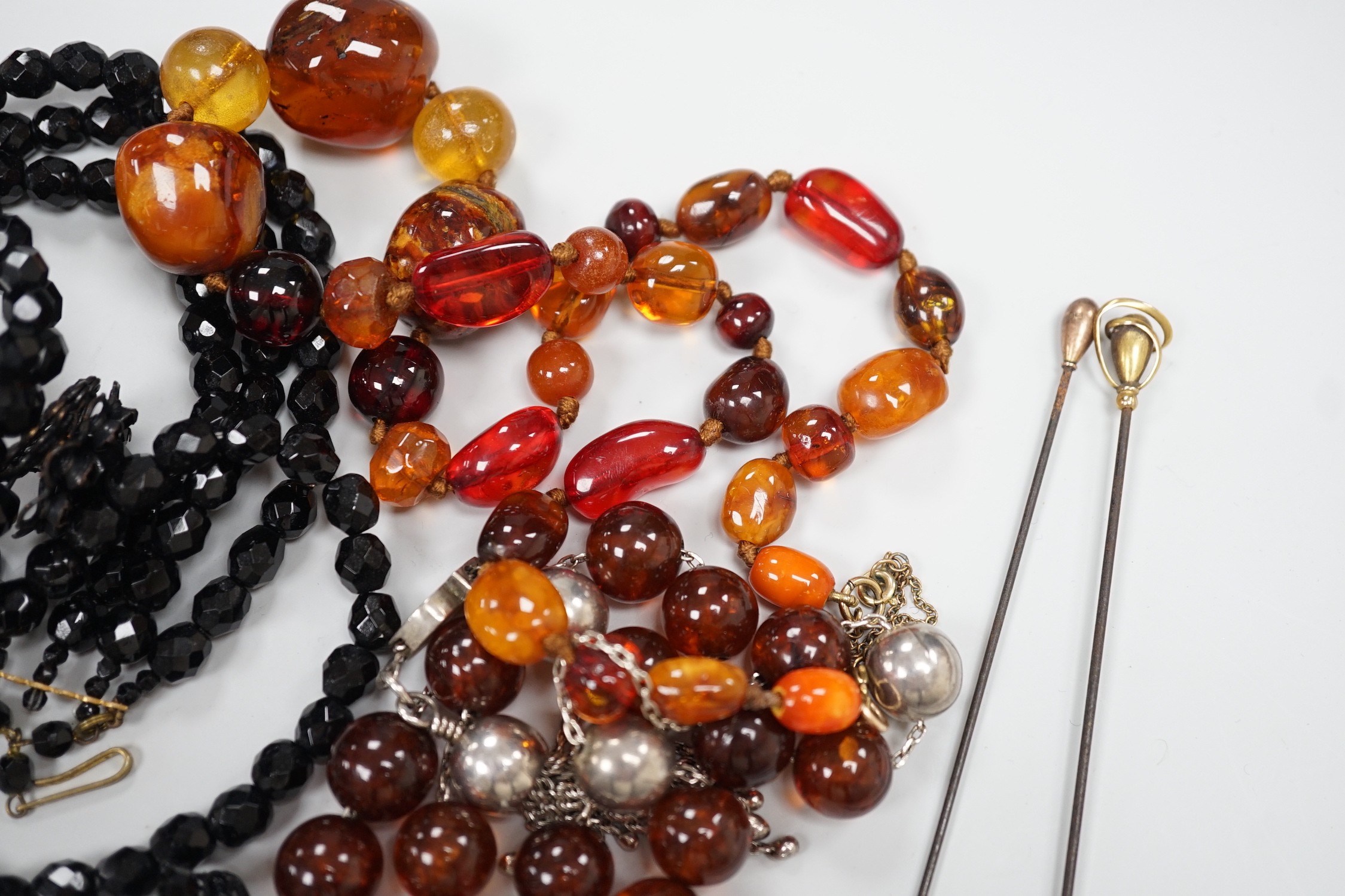 An early 20th century 9ct gold mounted hat pin by Charles Horner, 16cm one other 9ct mounted hat pin, a Margaret Haskell brooch and bracelet and three other items including amber necklace.